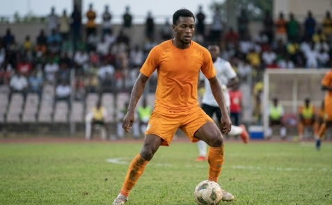 Footballeur nigérien en action avec le ballon lors d’un match international, ambiance réaliste et sans artifice.